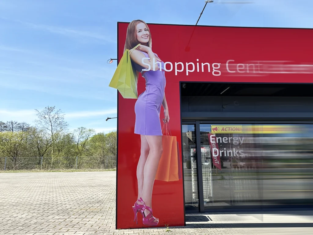 czerwone tablice z napisem shopping center i wystającą dziewczyną z zakupami jako tablica reklamowa